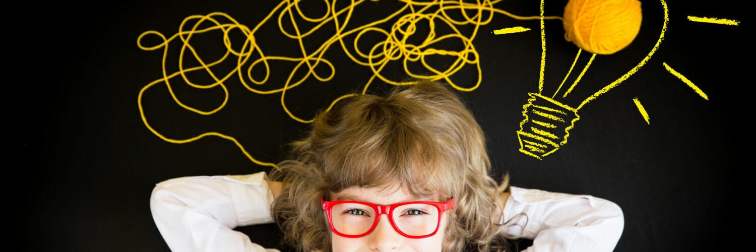 Child wearing red glasses beneath yellow yarn and a chalk-drawn light bulb